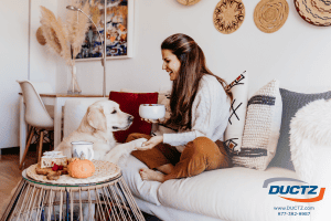 A woman sits in her living room with her dog after air duct cleaning