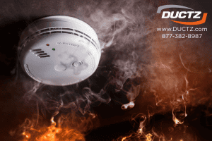 Smoke detector surrounded by smoke and flames