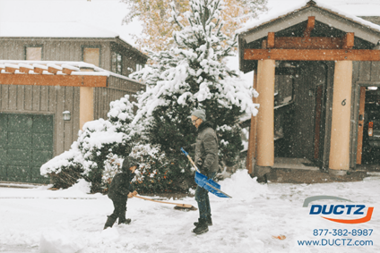 Father and son play in the snow while shoveling