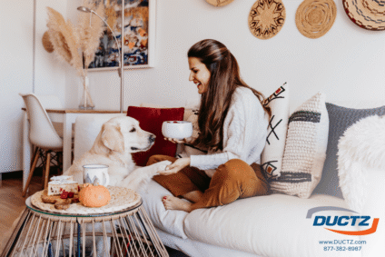 A woman sits in her living room with her dog after air duct cleaning