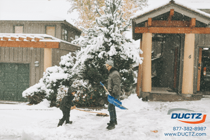 Father and son play in the snow while shoveling